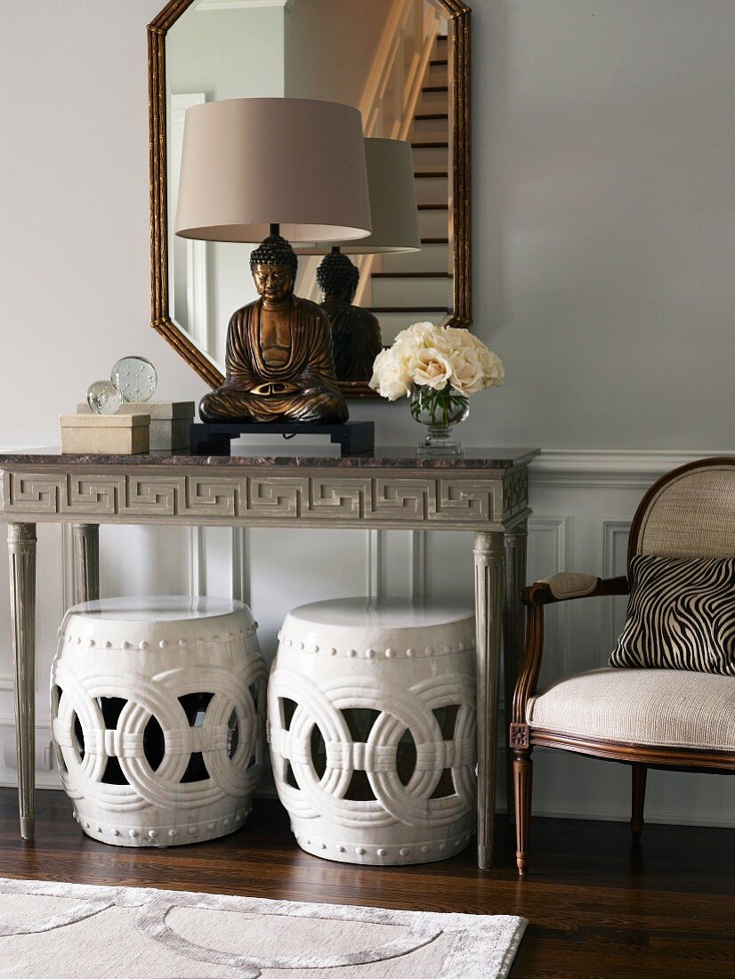 Buddha statue on console table above two stools