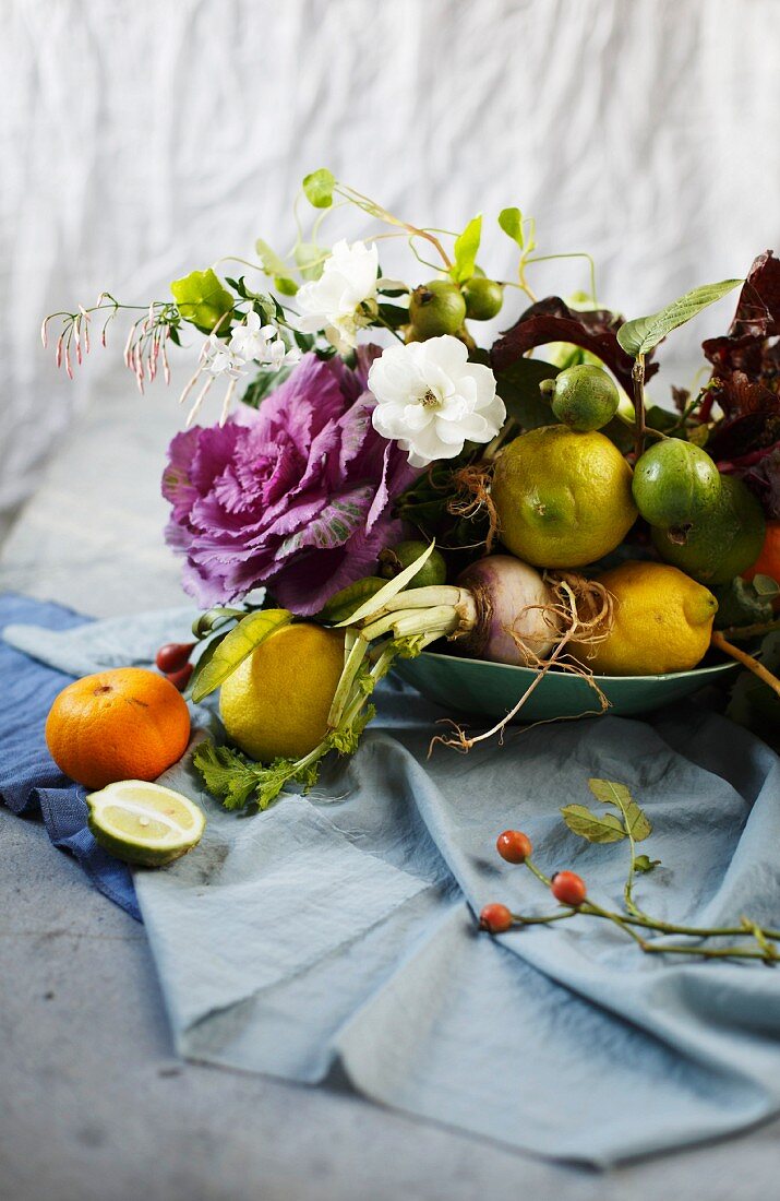 Arrangement aus Blüten, Zweigen, Obst und Gemüse