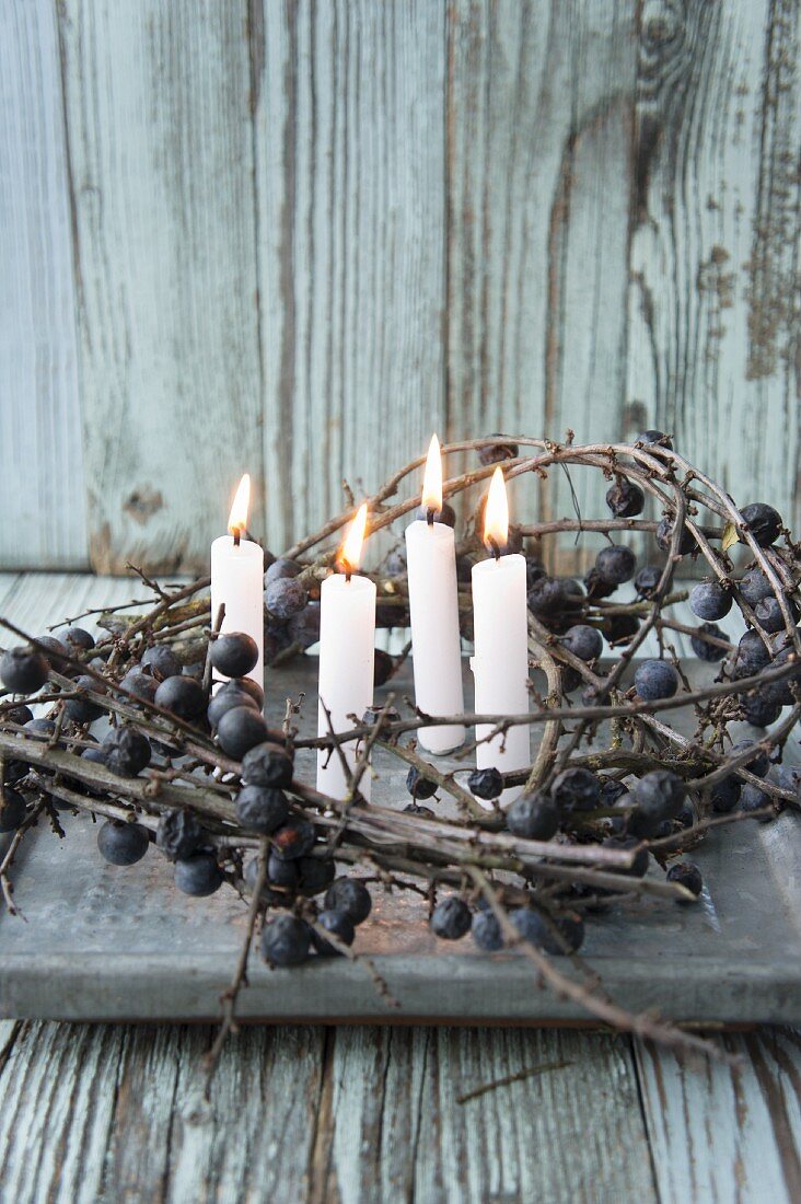 Four lit candles in wreath of sloe branches