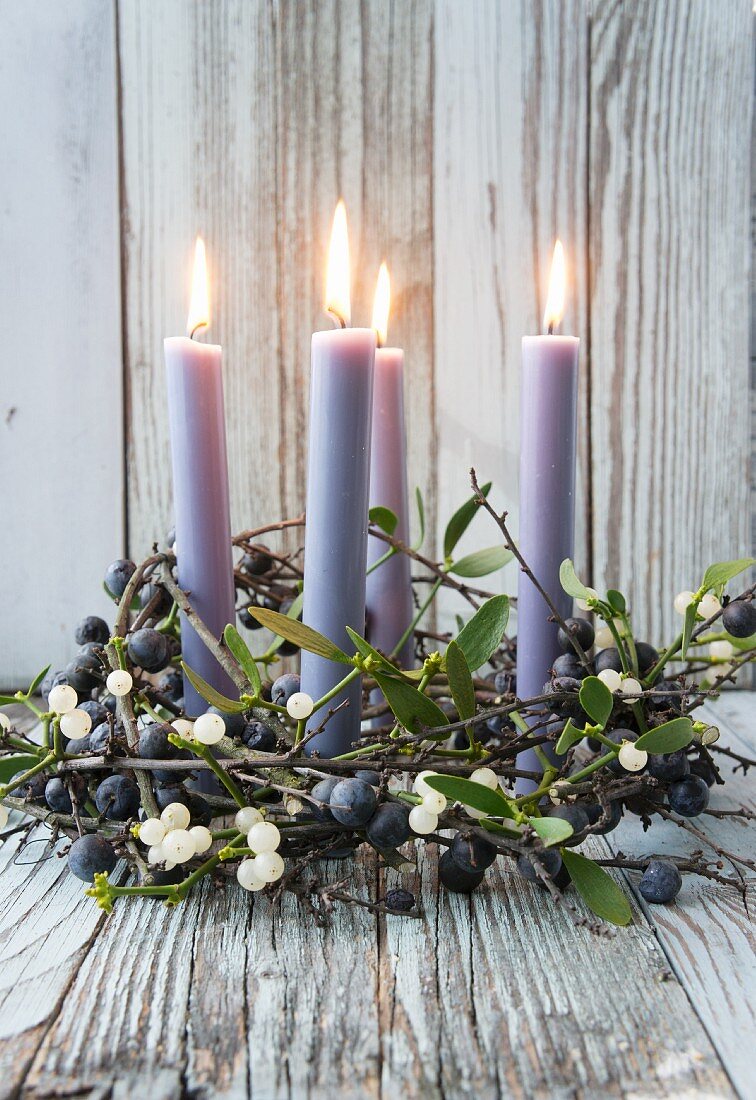 Four candles in wreath of sloe branches and mistletoe