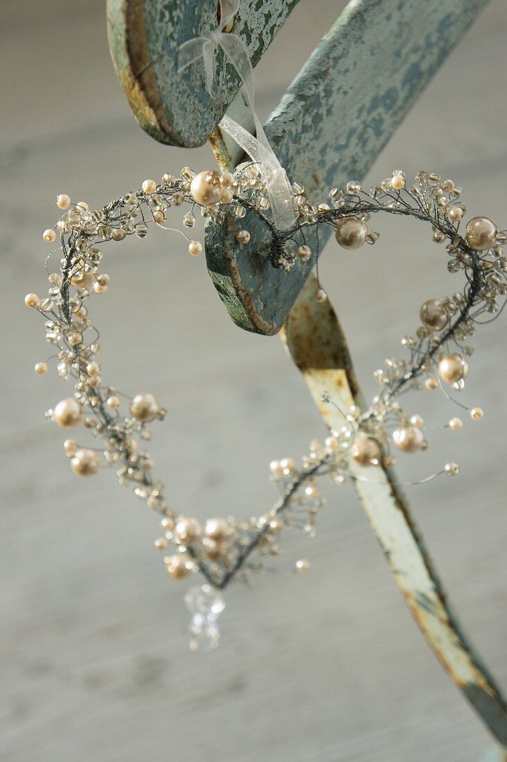 Romantisches Dekoherz mit Perlen an einem verwitterten Stuhl