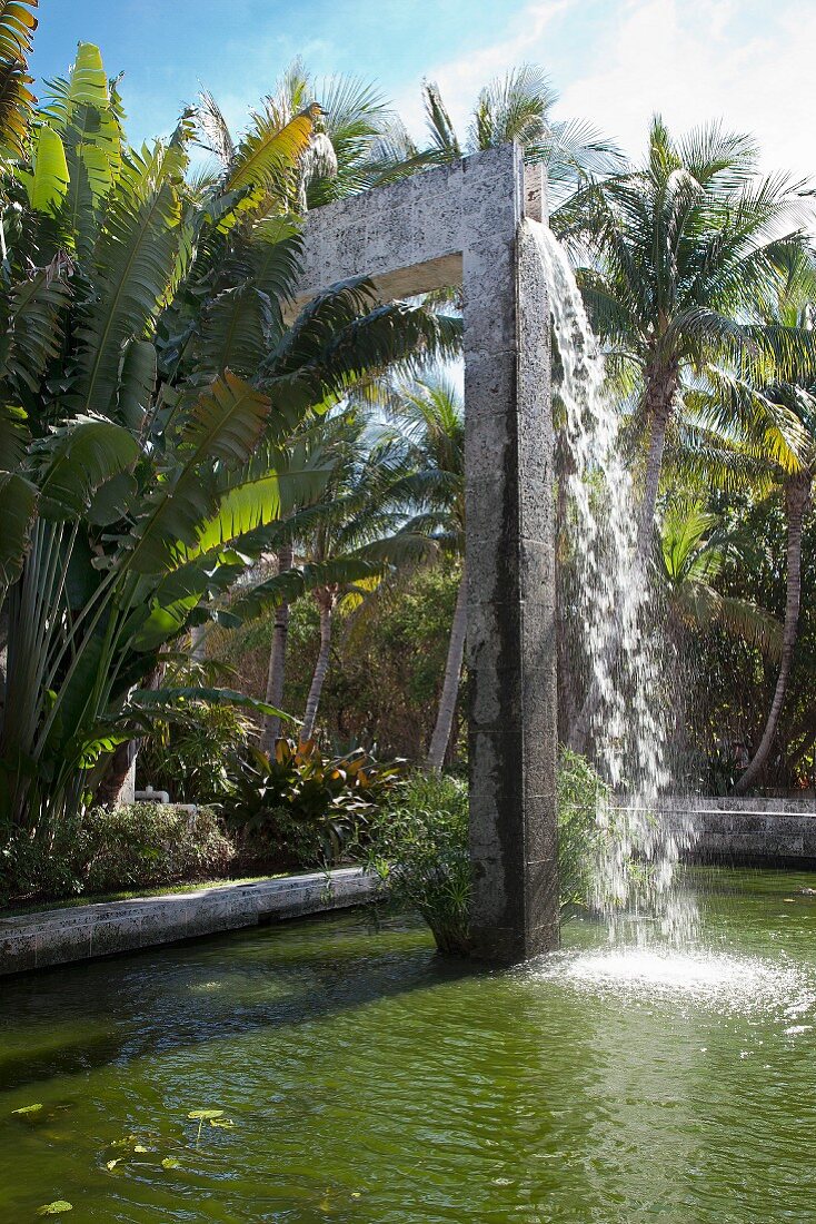 Waterfall falling into pool in tropical garden