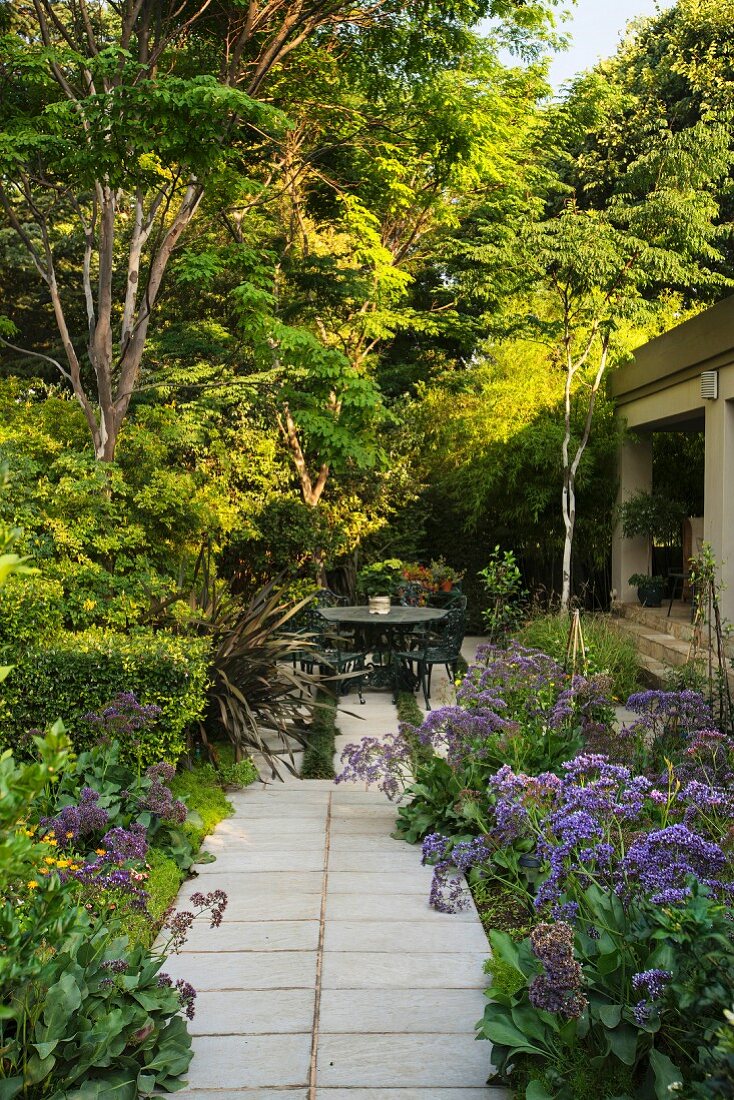 Path leading through summery garden to seating area outside house