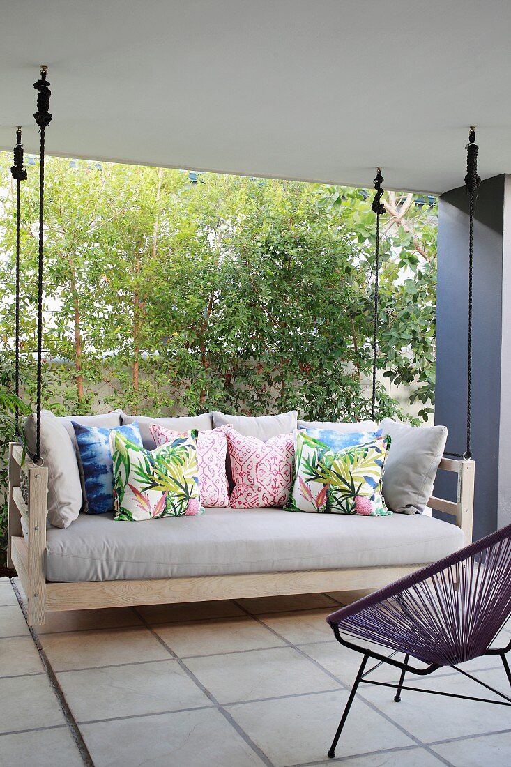Swing couch with colourful scatter cushions on roofed terrace