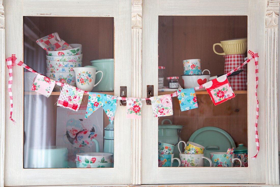 Hand-sewn bunting and floral crockery on shelves of kitchen dresser