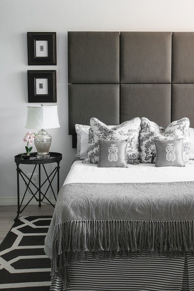 Bed with upholstered headboard in elegant bedroom in shades of grey