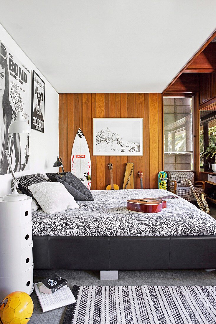 Youth room with black and white bed, surfboard and musical instruments