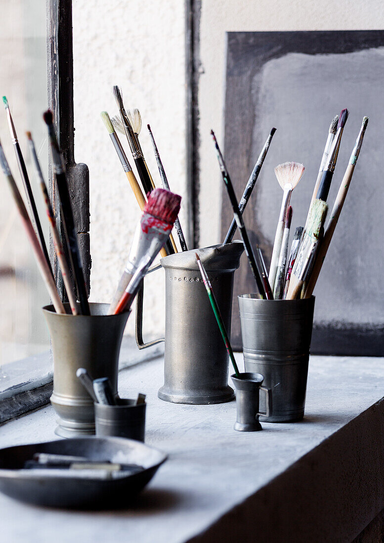 Paintbrushes and painters' utensils in pewter measuring cups and trophies