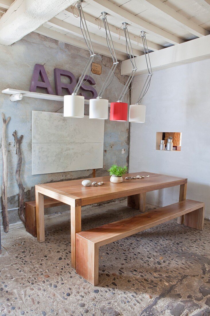 Schlichter Edelholztisch mit Holzbänken, darüber Designerleuchten