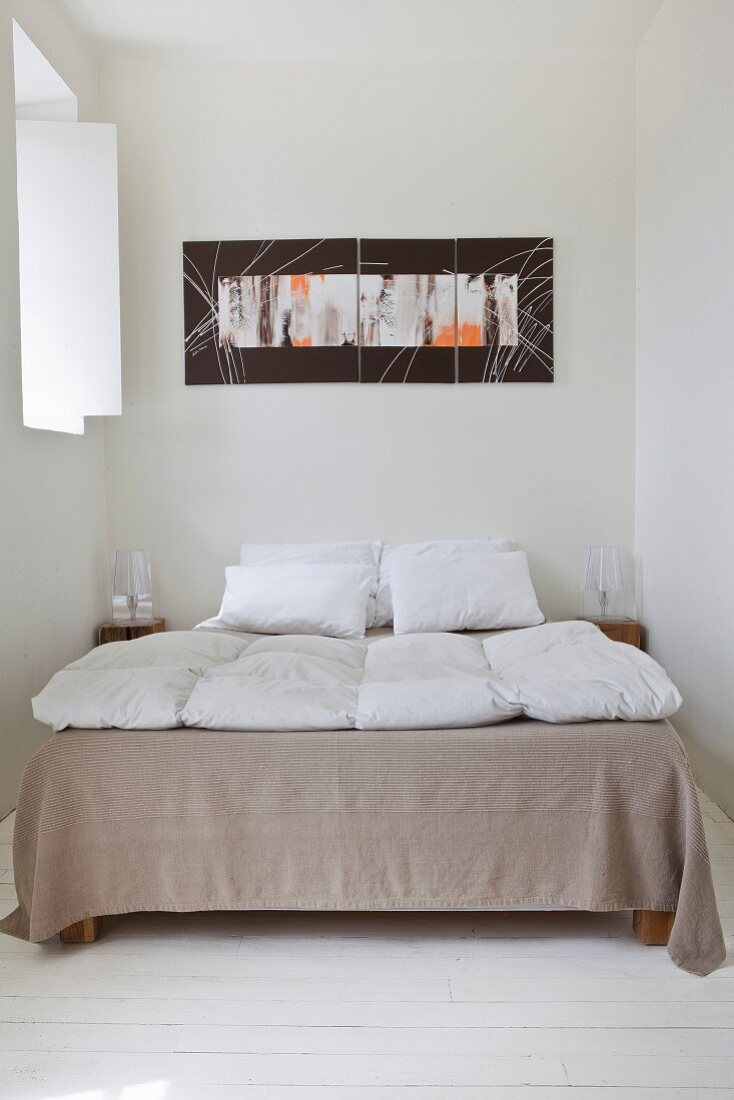 Doppelbett und moderne Kunst in Schlafzimmer mit weißem Dielenboden