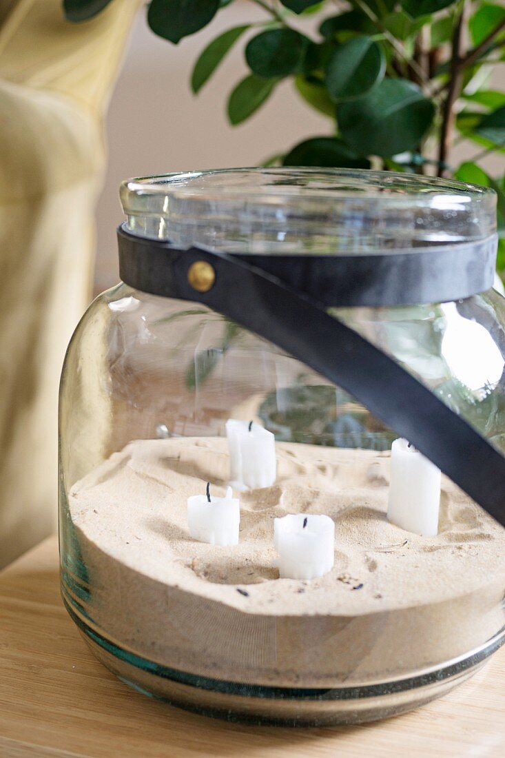 Sand and white candles in glass jar