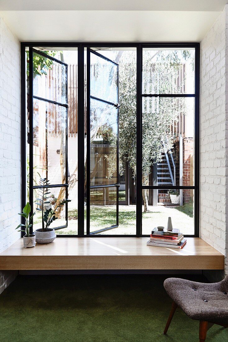 Fensterbank mit Zimmerpflanzen und Bücherstapel