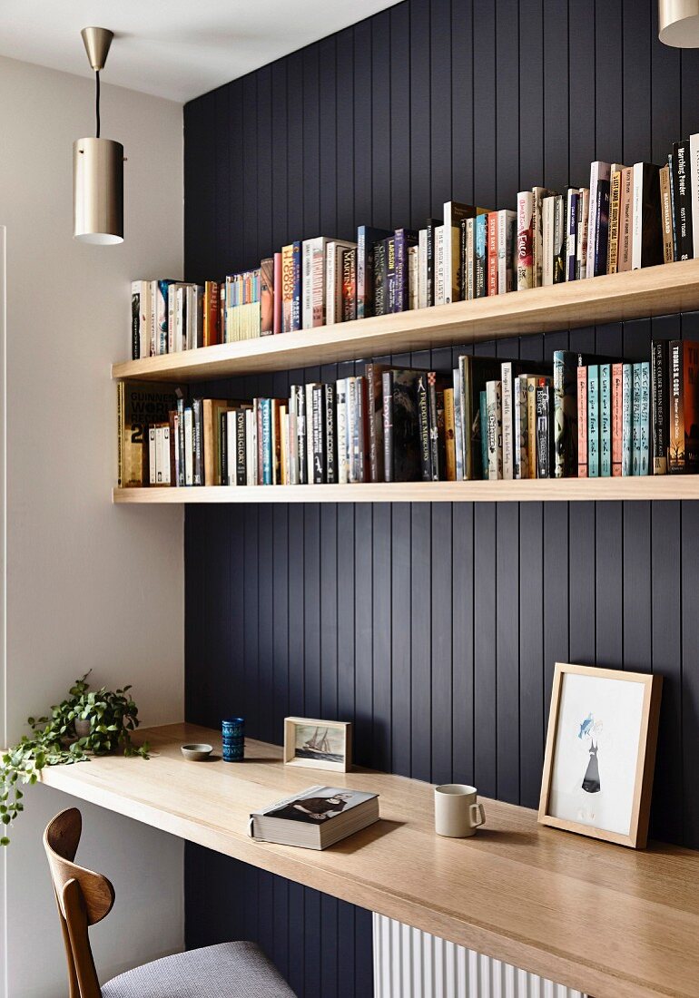 Schwarze Holzverkleidung mit Bücherboards über Schreibtischplatte