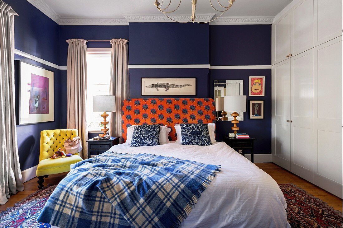 Doppelbett im Schlafzimmer mit dunkelblauer Wand und weißem Einbauschrank