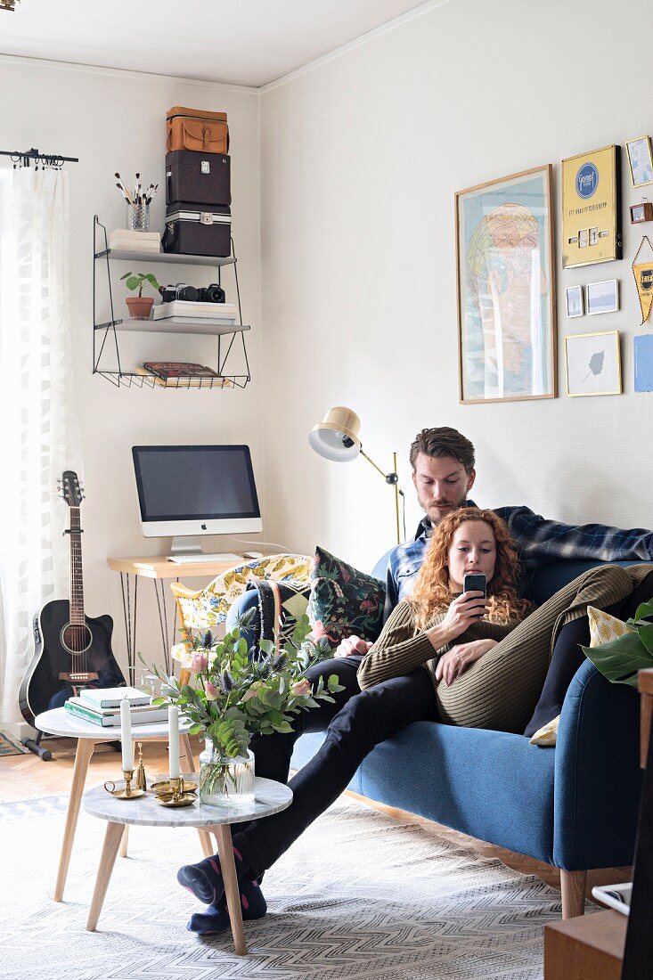 Young couple on blue sofa in retro living room