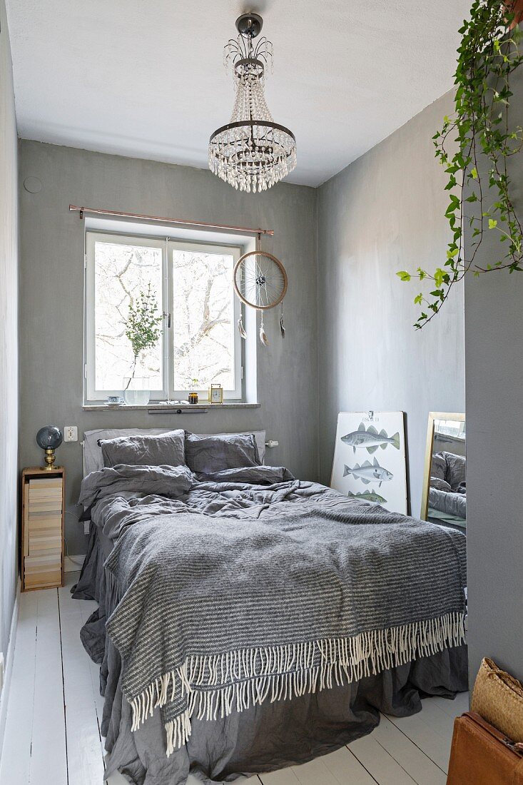 Schlafzimmer in Grautönen mit weißem Dielenboden, Kronleuchter und Traumfänger