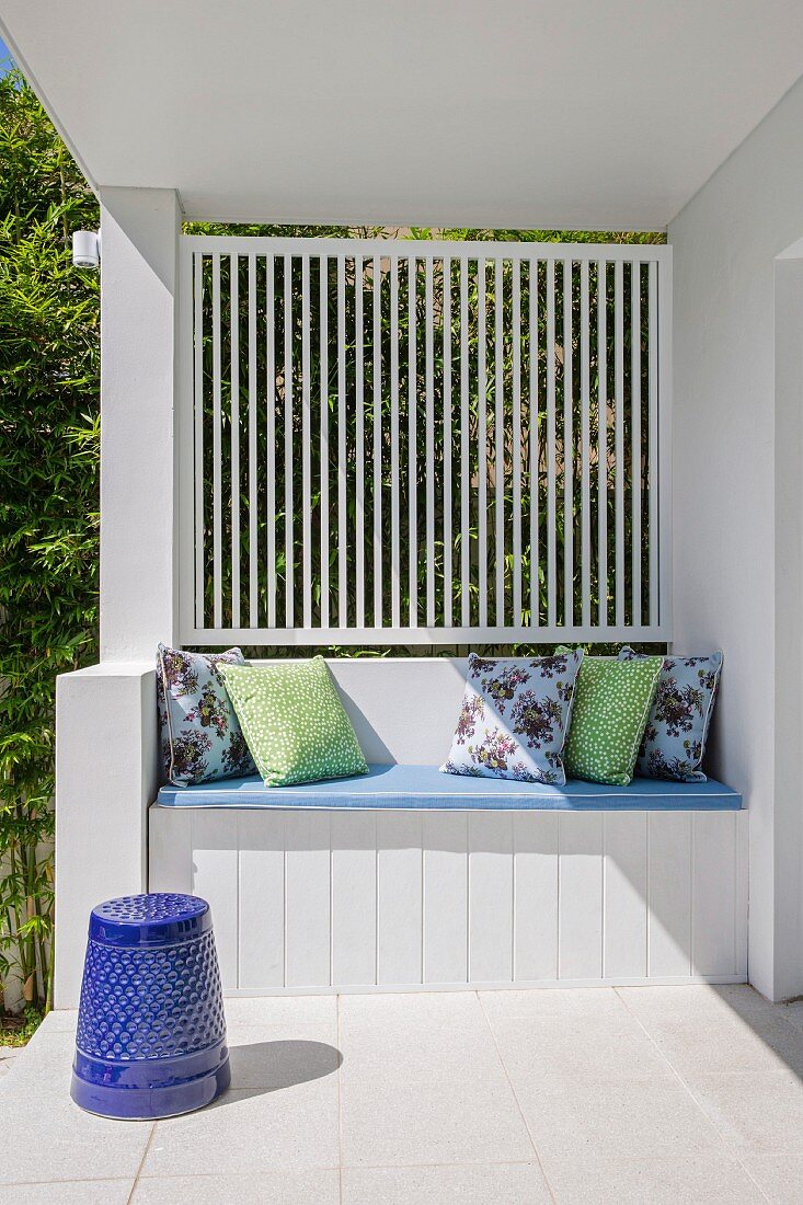 Built-in bench with cushion and decorative pillows on white veranda