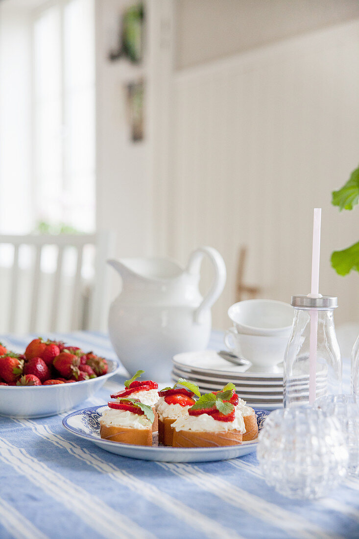 Open-faced sandwiches of cream cheese and strawberries on set table