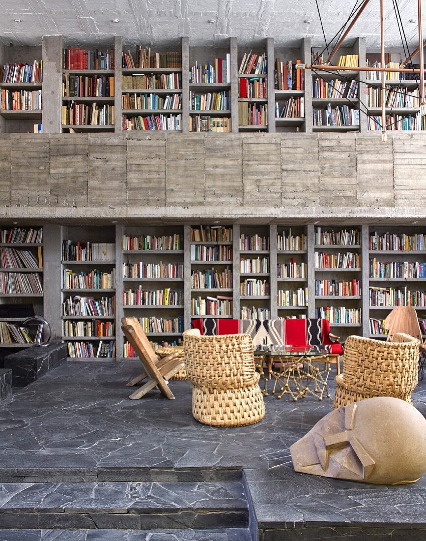 Offener Wohnraum mit Bücherwand in einem Haus aus Beton