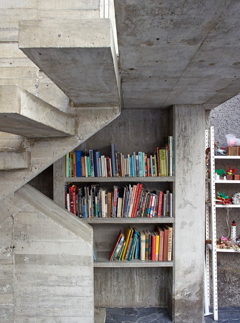 Bücherregale unter der Treppe in einem Haus aus Beton