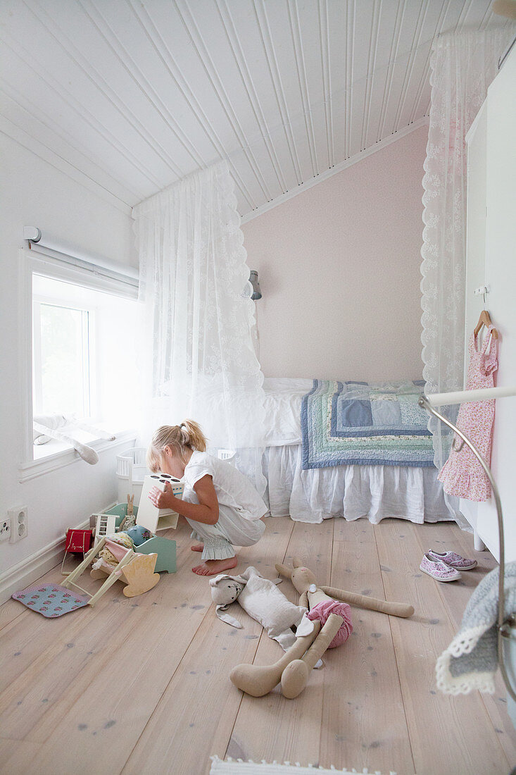 Girl playing with dolls' furniture in bedroom