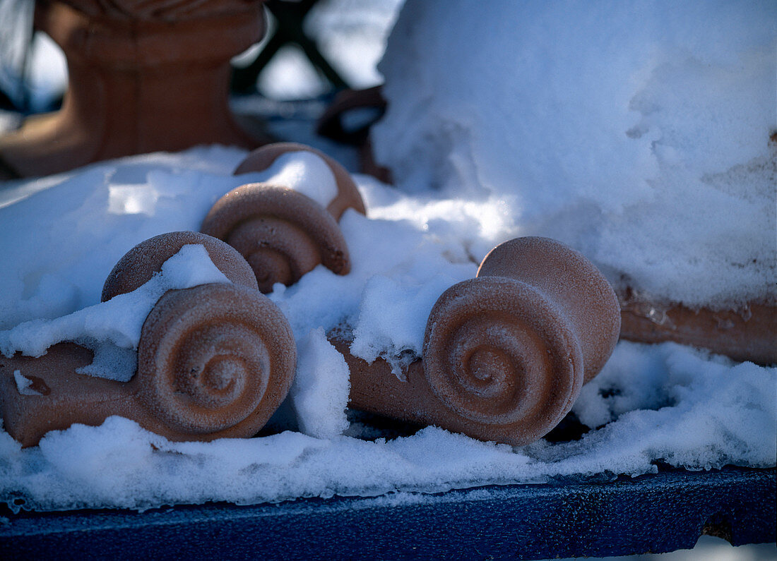 Terracotta-Füße als Untersetzer für Töpfe im Schnee.