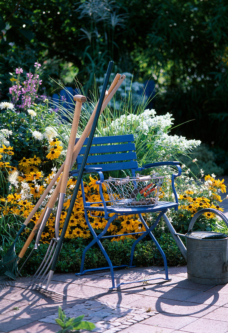 Gartenwerkzeug an blauen Stuhl gelehnt