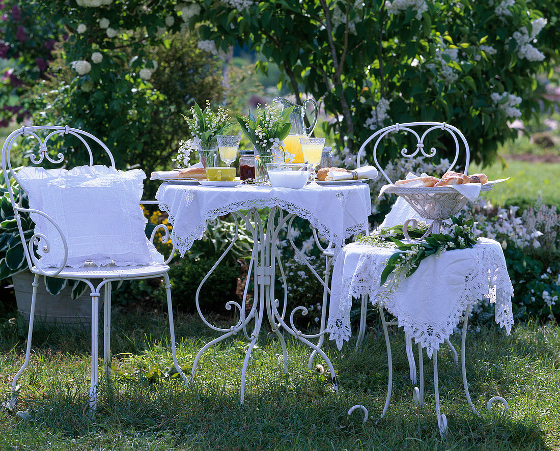 White seat in front of white flowering shrubs, Convallaria