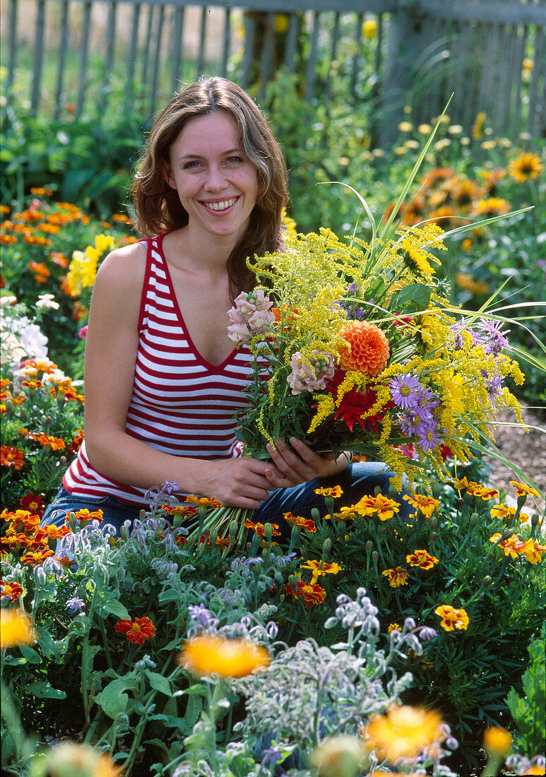 Junge Frau pflückt Blumenstrauß in Bauerngarten