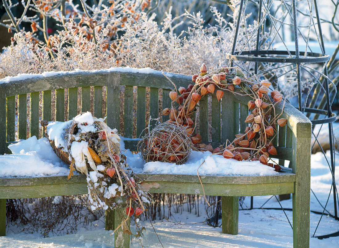 Gartenbank im Winter dekoriert mit Kranz aus Physalis
