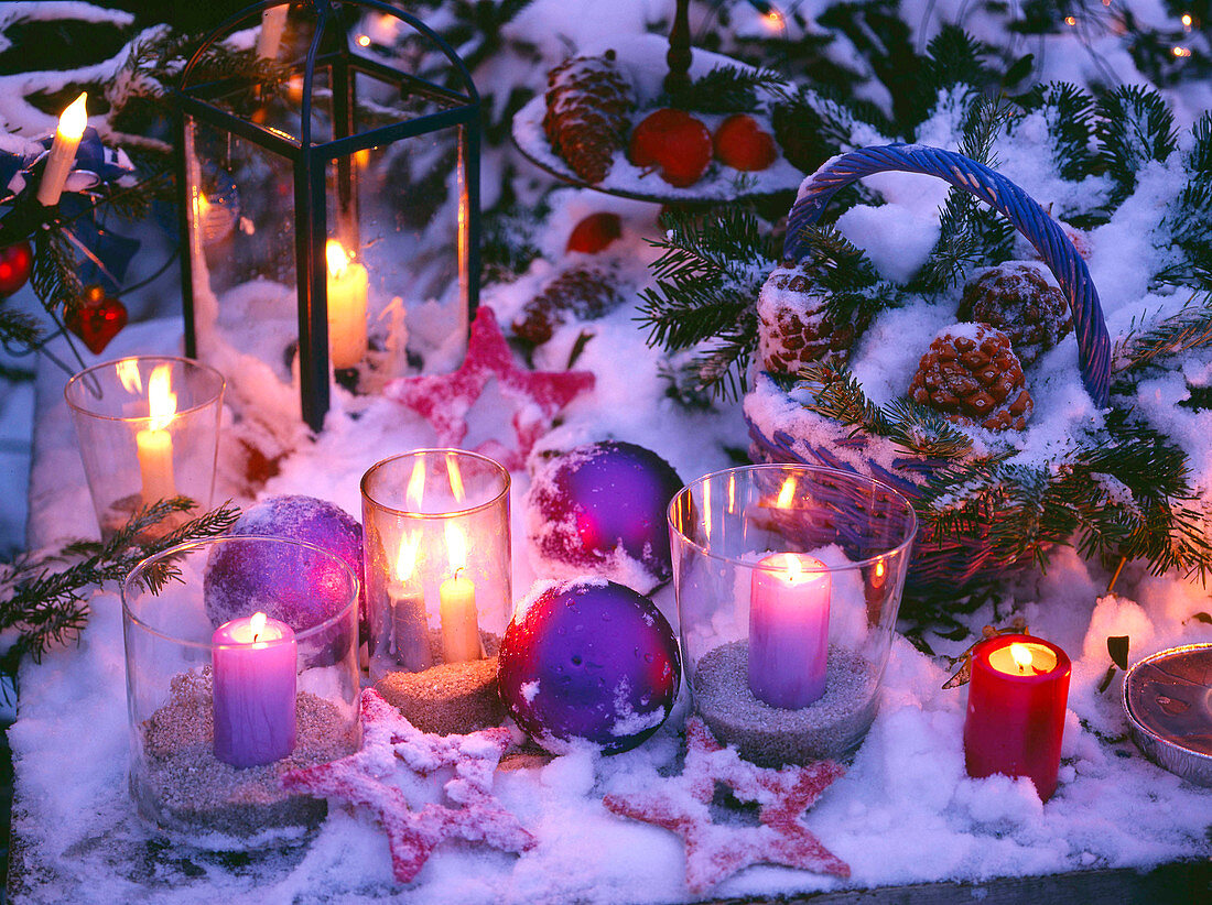 Lantern and candles in glasses placed in the snow, balls, stars, basket