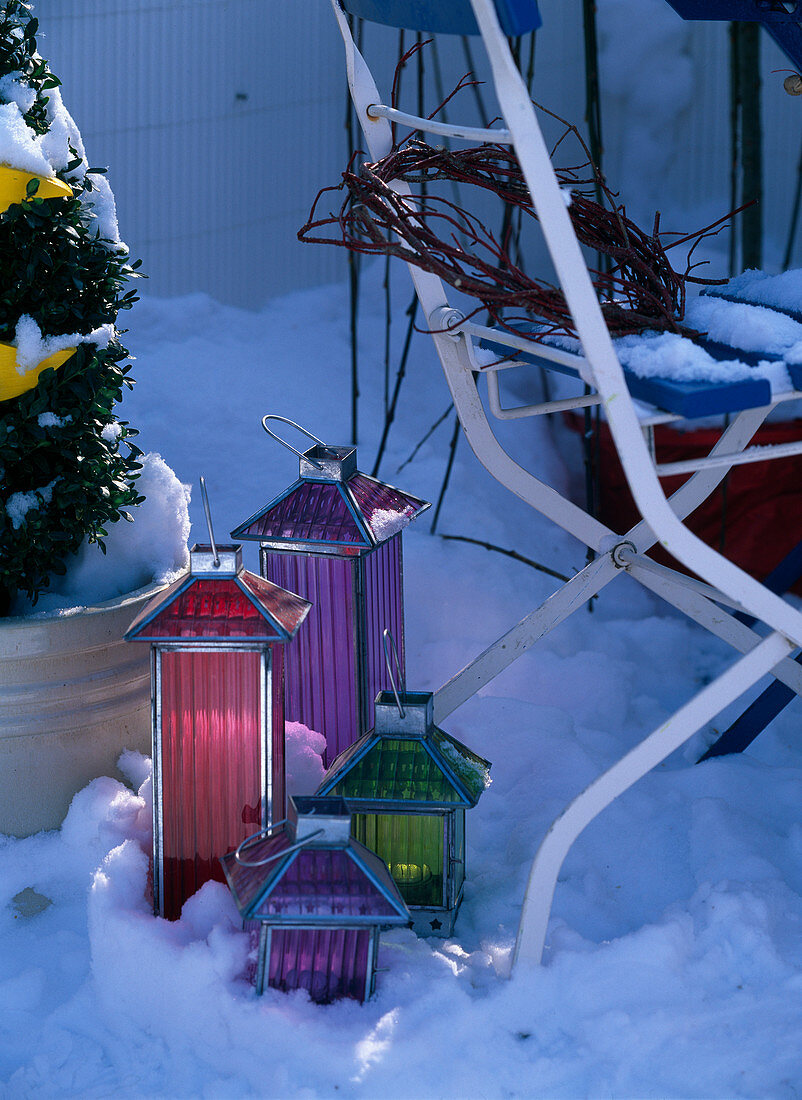 Bunte Windlichter im Schnee auf dem Balkon