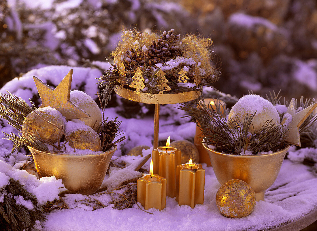 Adventsdeko mit Schnee und Rauhreif, Zapfen, Kiefernzweig, Goldkugeln, Kerzen un