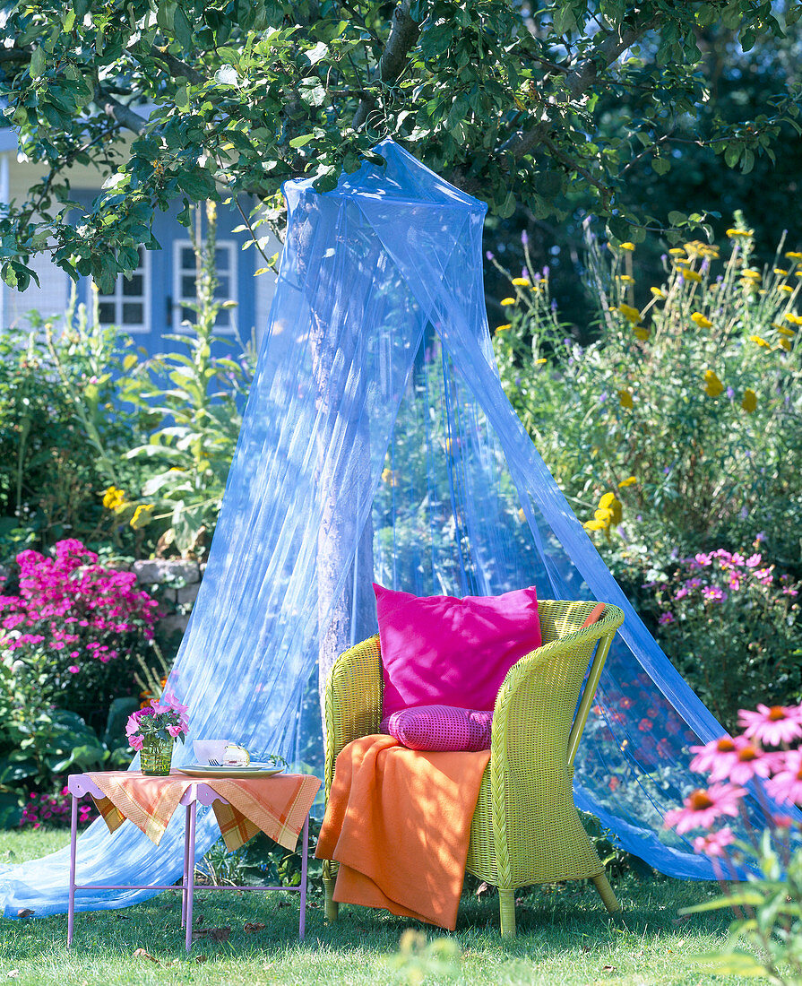Green wicker armchair under blue mosquito net