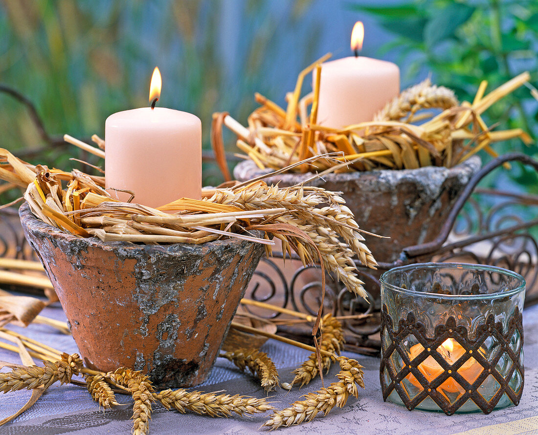 Candles in rustic pots with triticum (wheat)