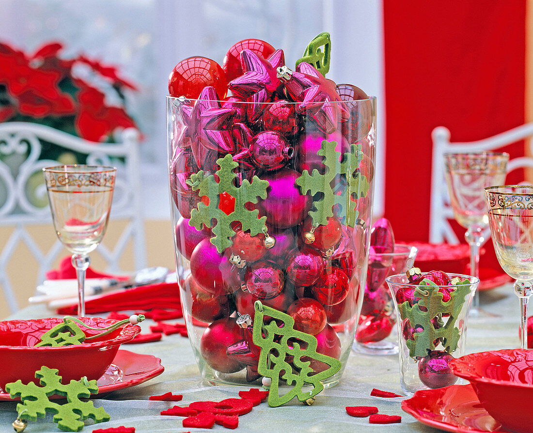 Red and pink tree decorations in a large glass vase, green felt tags