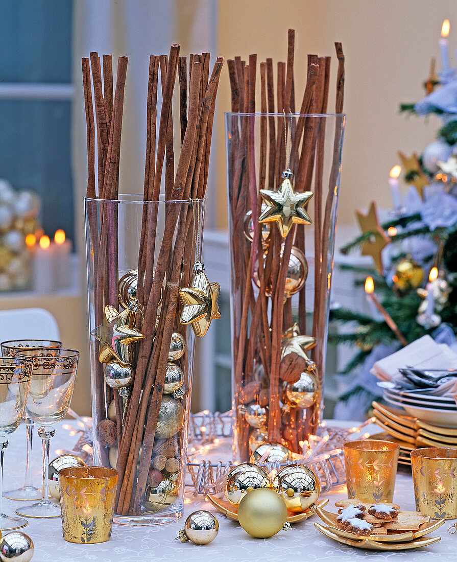 Glasses filled with cinnamon sticks, nuts and golden tree decorations, tableware