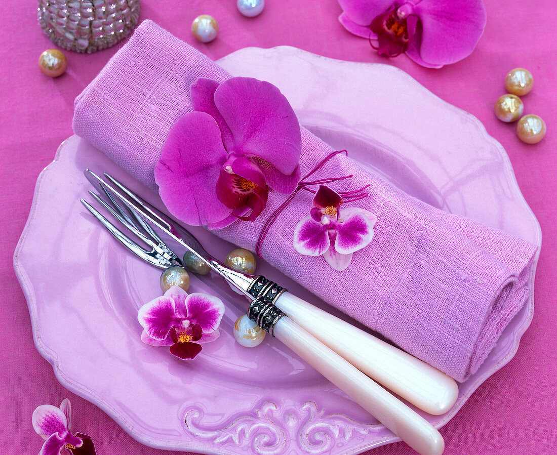 Blossoms of phalaenopsis on rolled pink napkin