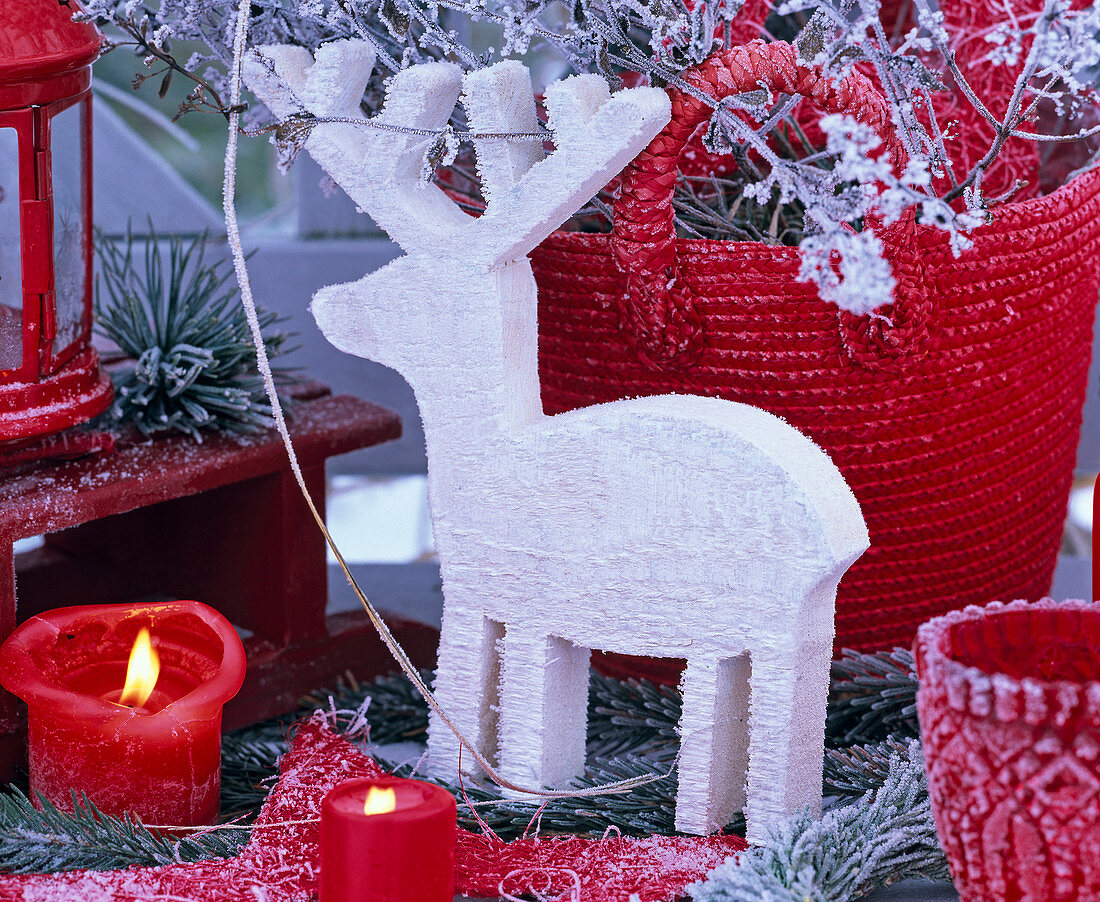 Weißer Elch aus Holz mit Rauhreif, rote Kerzen, rote Tasche