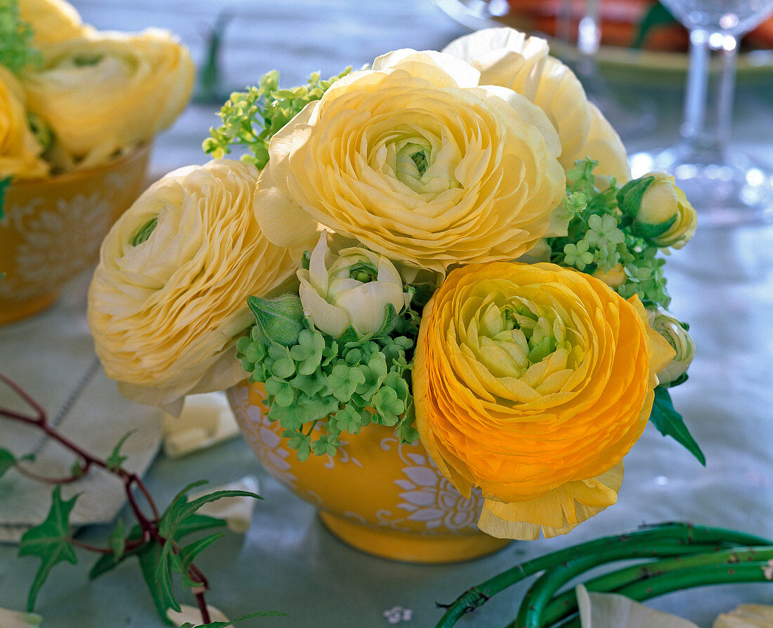 Ranunculus and viburnum bouquet in yellow shell