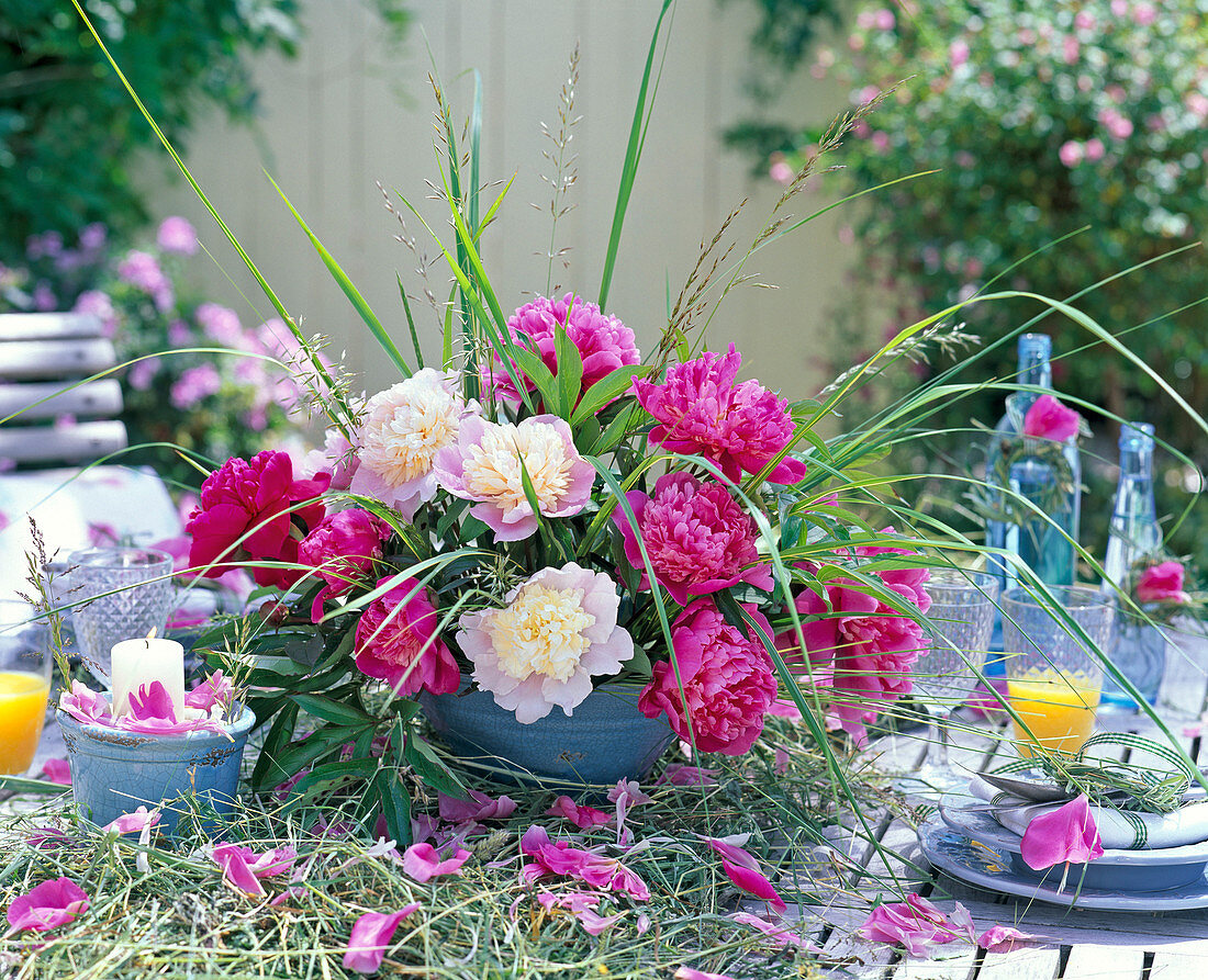 Arrangement of paeonia and grasses on table runner made of hay