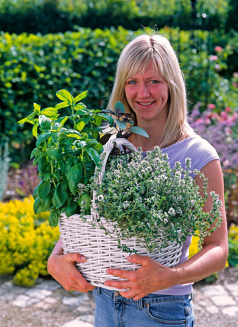 Woman with herbs in white handle basket