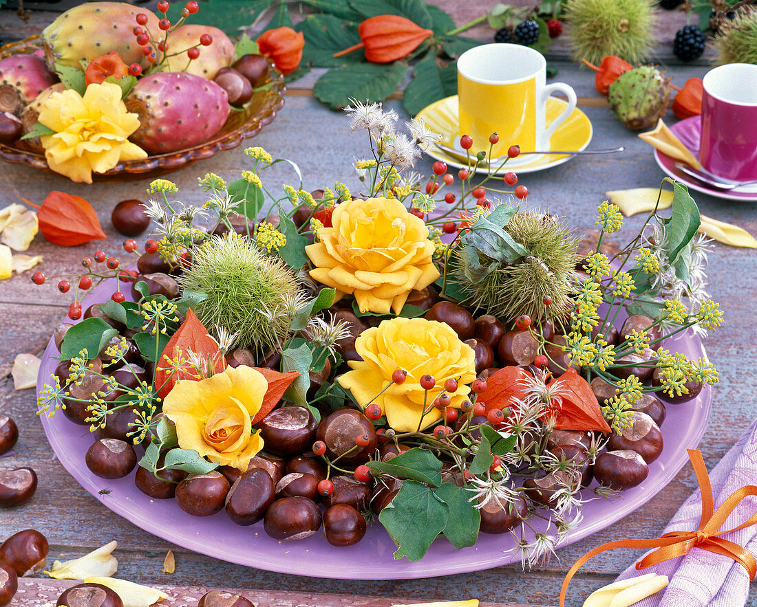 Herbstliche Dekoration mit Rosen, Beeren und Früchten