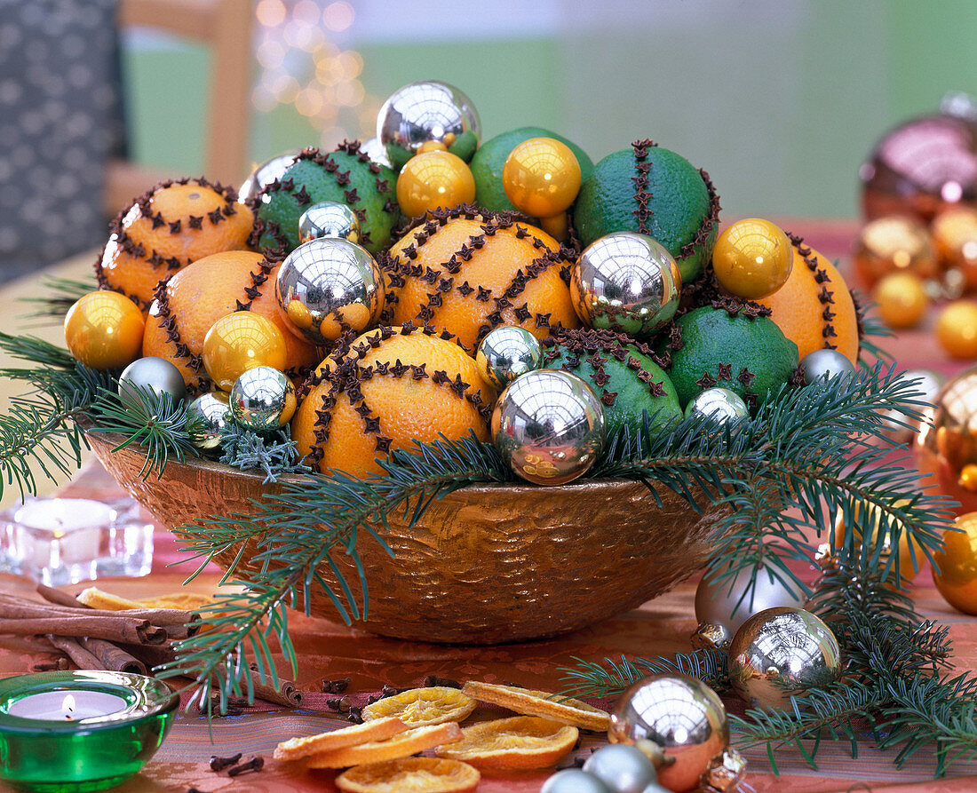 Citrus (Orangen, Limetten), Gewürznelken, silberne Weihnachtsbaumkugeln, Zweige