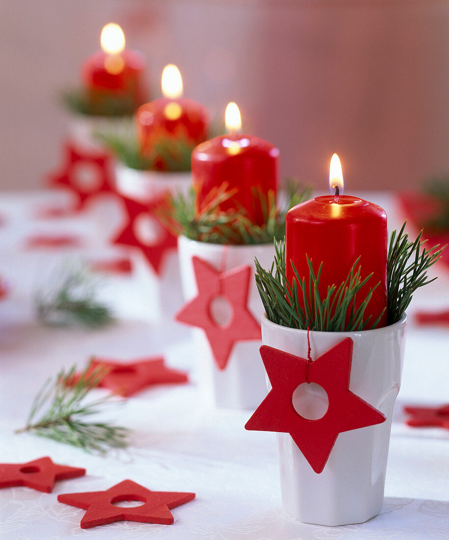 Christmas wreath with pinus in white cups with red candles and stars