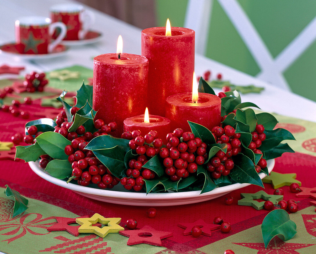 Adventskranz aus Ilex (Stechpalme) mit roten Kerzen auf weißem