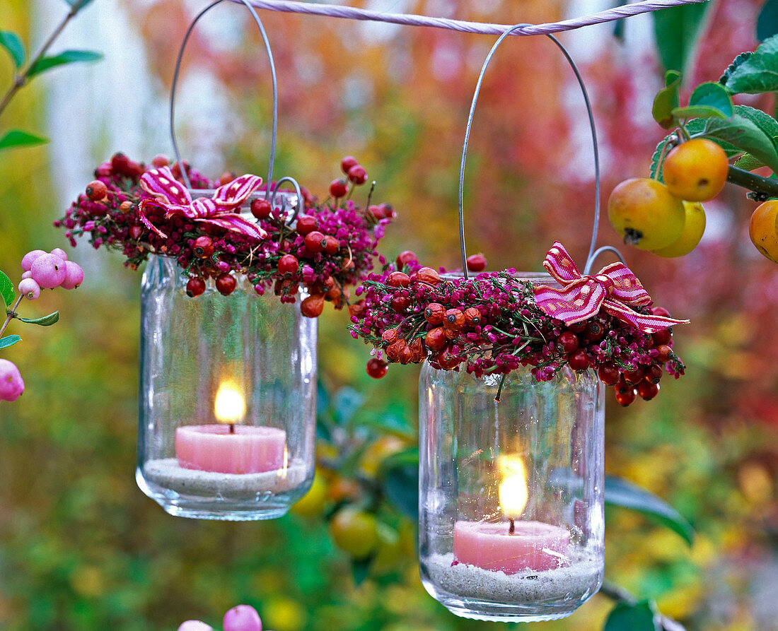 Kränze aus Rosa (Hagebutten), Erica (Heide) um Windlichter mit rosa Kerzen