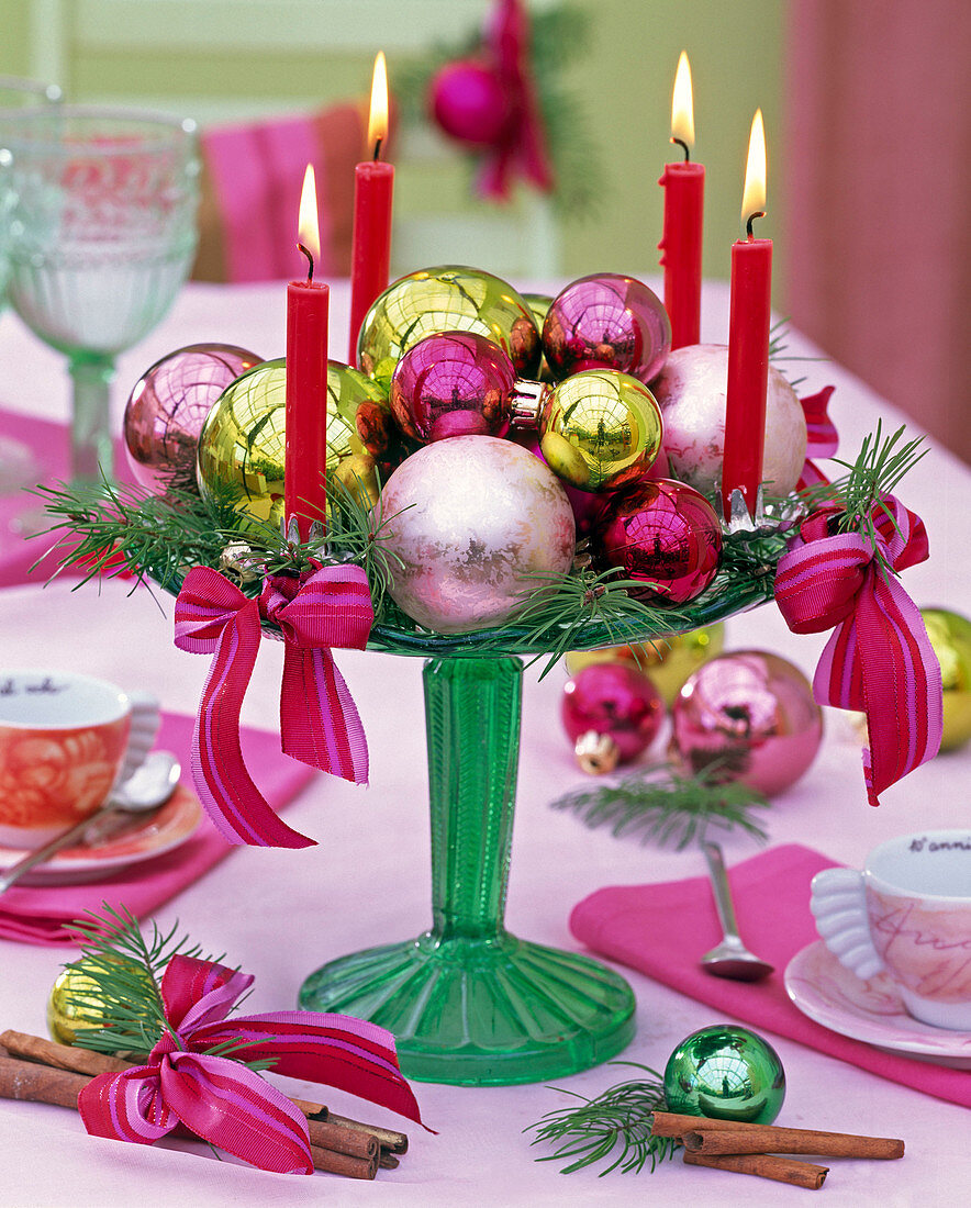 Adventskranz aus roten Kerzen, Weihnachtsbaumkugeln, Schleifen