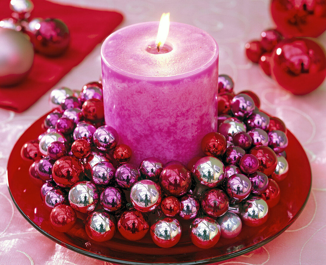 Kerzenkranz aus kleinen Weihnachtsbaumkugeln mit pinkfarbener Stumpenkerze