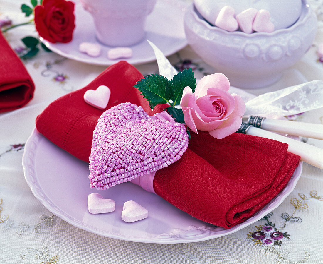 Rosa (Rose) auf roter Serviette, Herz mit Pailletten besetzt, Brauseherzen
